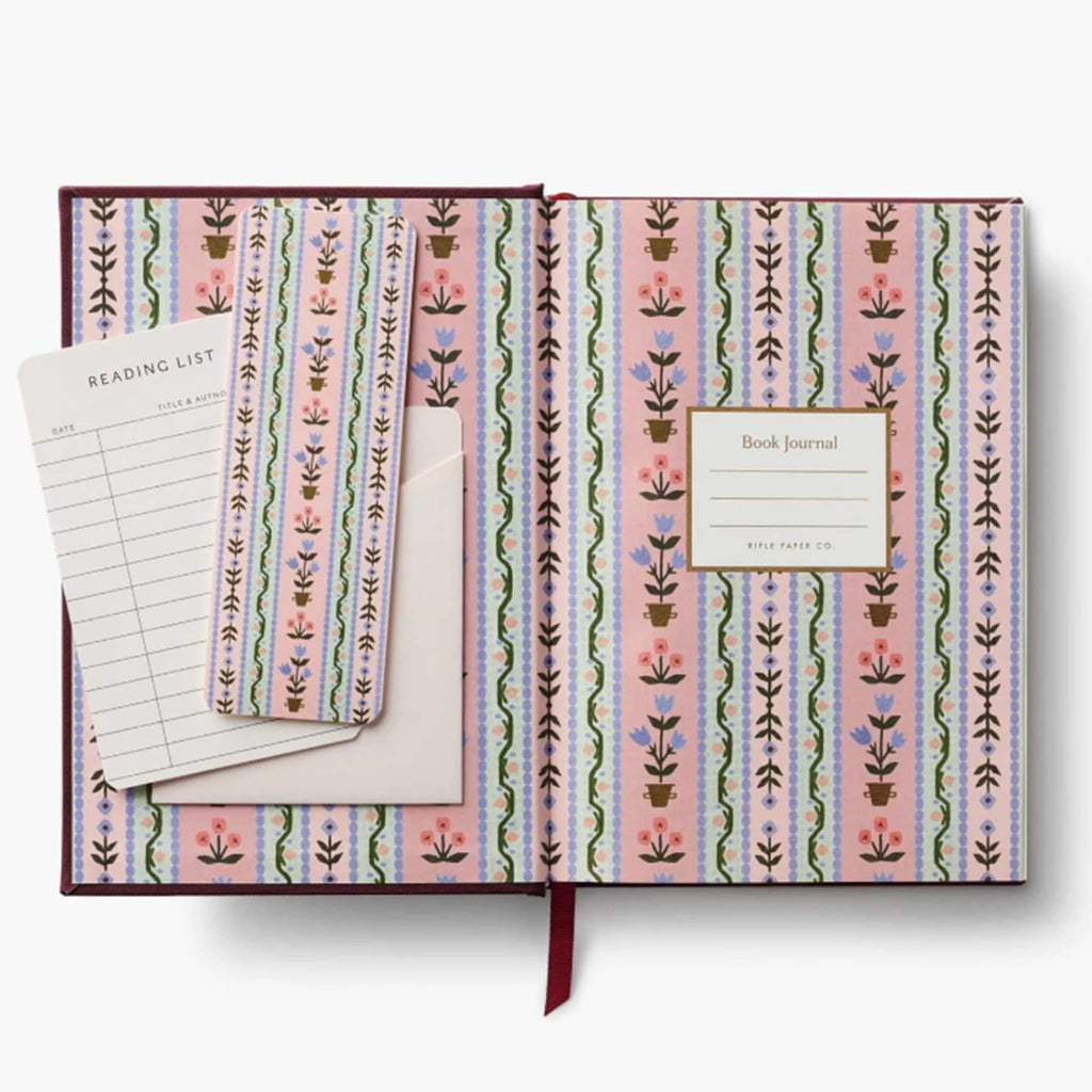 Inside cover of a book journal with colorful floral print, bookmarks and a reading list card that looks like old library checkout on a white background.