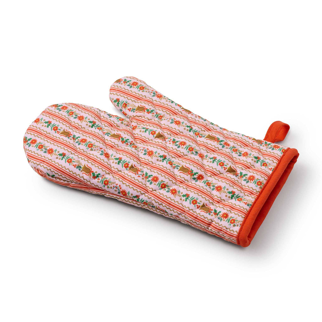 Decorative oven mitt with floral and bell pattern in pink and red, side angle view, on a white background.