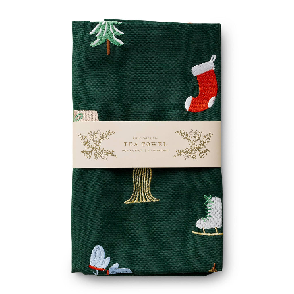 Dark green tea towel with embroidered Christmas-themed patterns in packaging, on a white background.