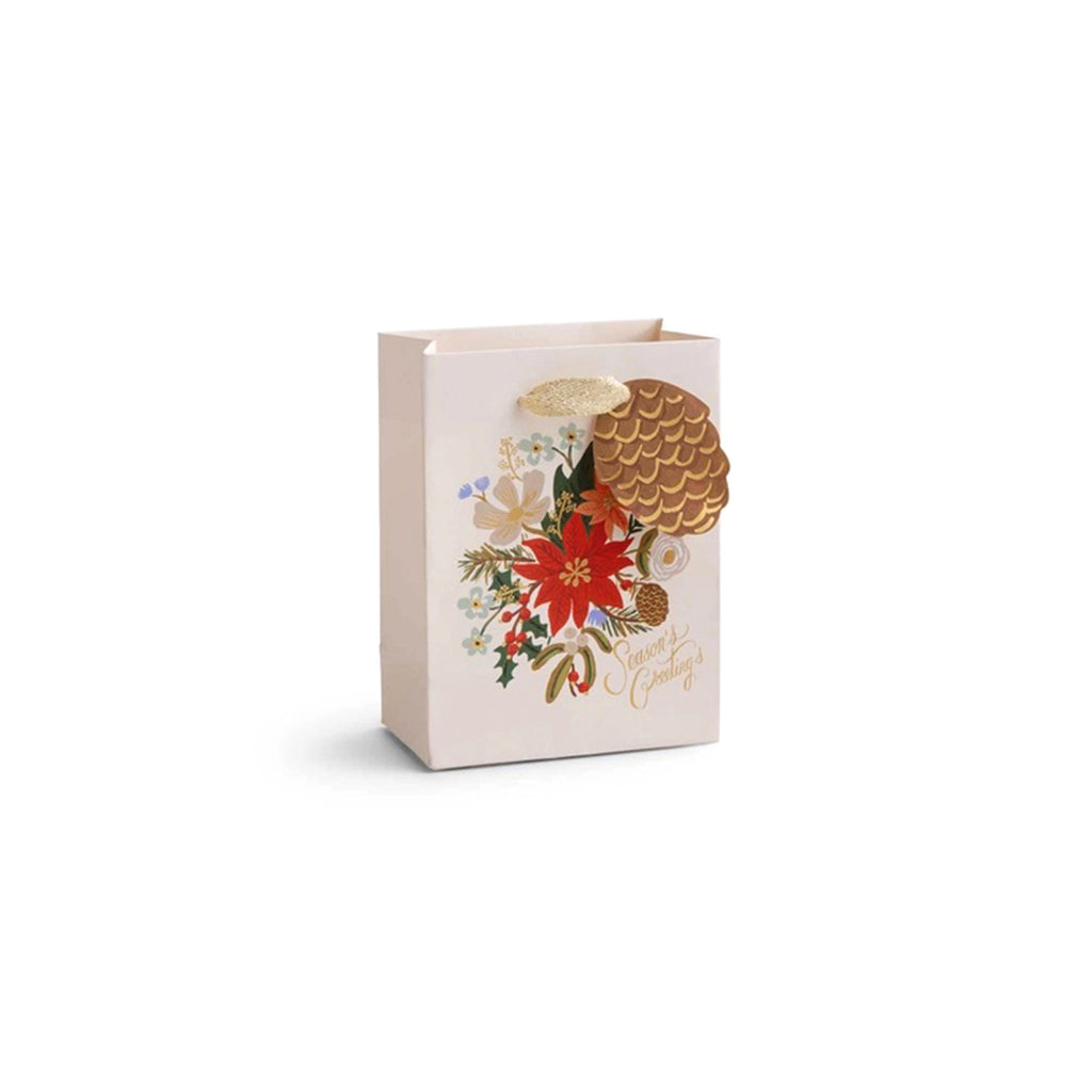 Rifle Paper Co. Holiday Bouquet Small Christmas Gift Bag, front view. Cream color bag with poinsettia floral design with pinecone "to" and  "from" tag, "Season's Greetings" in gold script lettering and ivory cotton ribbon handles.