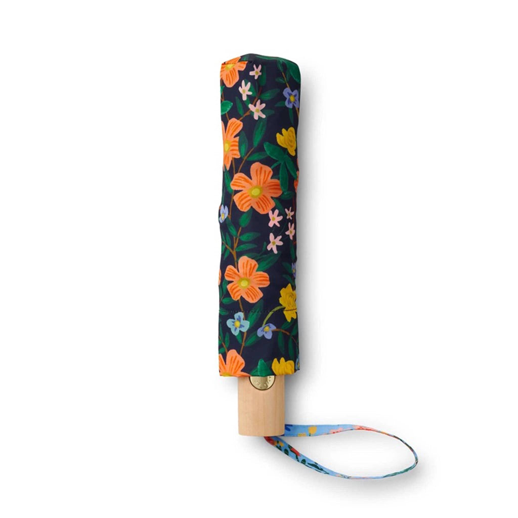 rifle paper company umbrella with wildwood floral print on sky blue and navy blue colorblock panels, closed, in matching pouch.