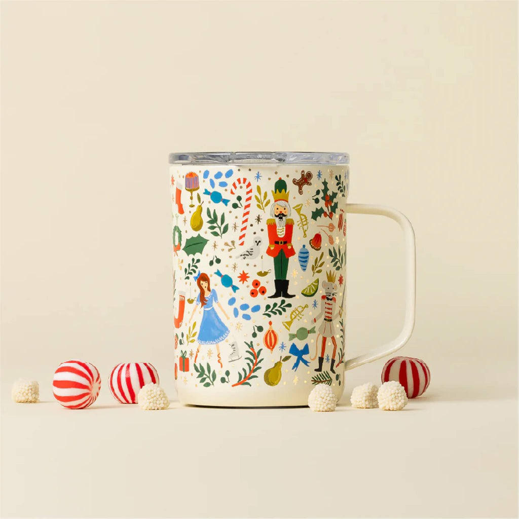 Rifle Paper Co. x Corkcicle 16 ounce stainless steel insulated mug with illustrated Nutcracker pattern on an ivory background and a clear plastic slide lid, front view with handle on the right side. Shown on matching ivory background with candies.