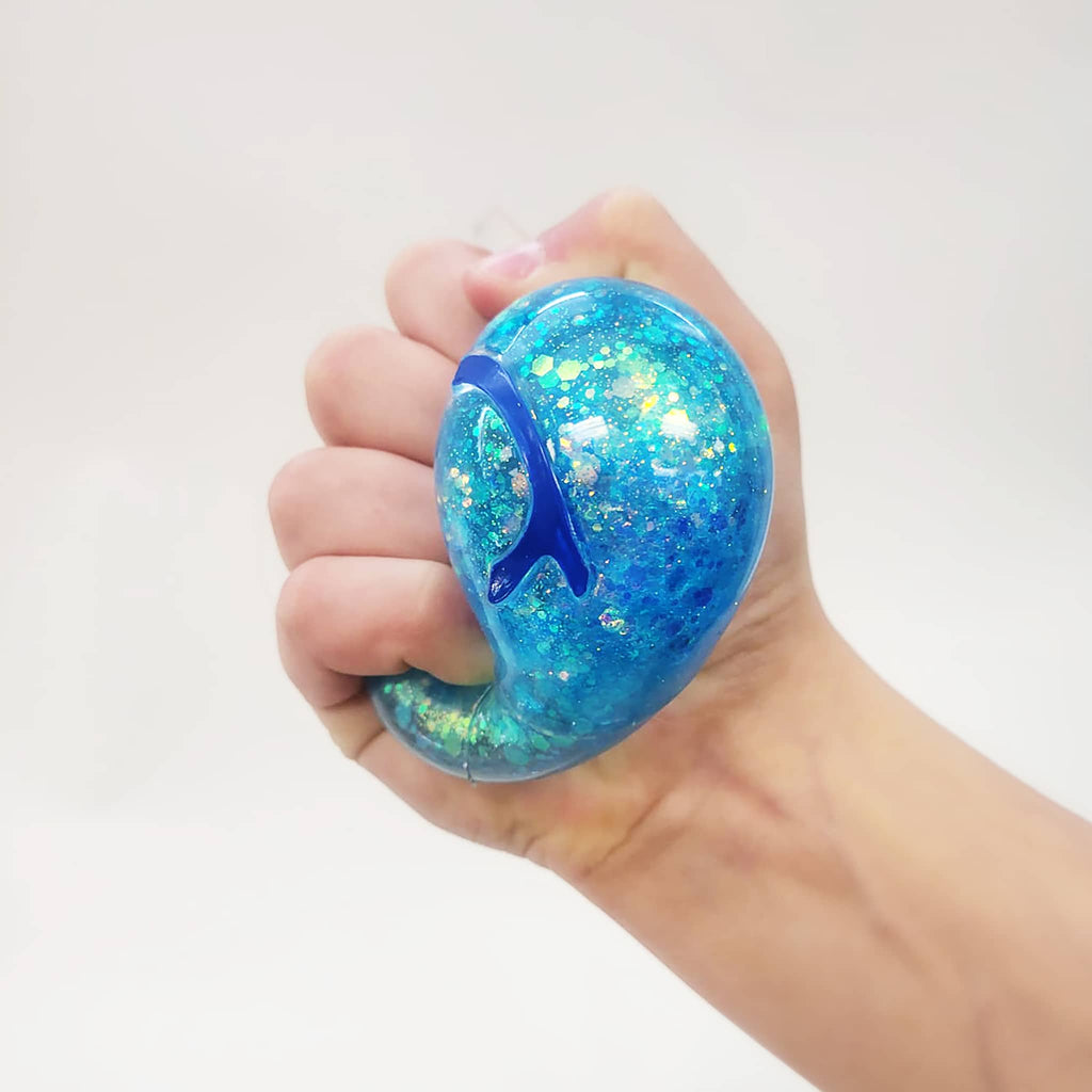 Hand squishing a blue dreidel stress ball against a white background.