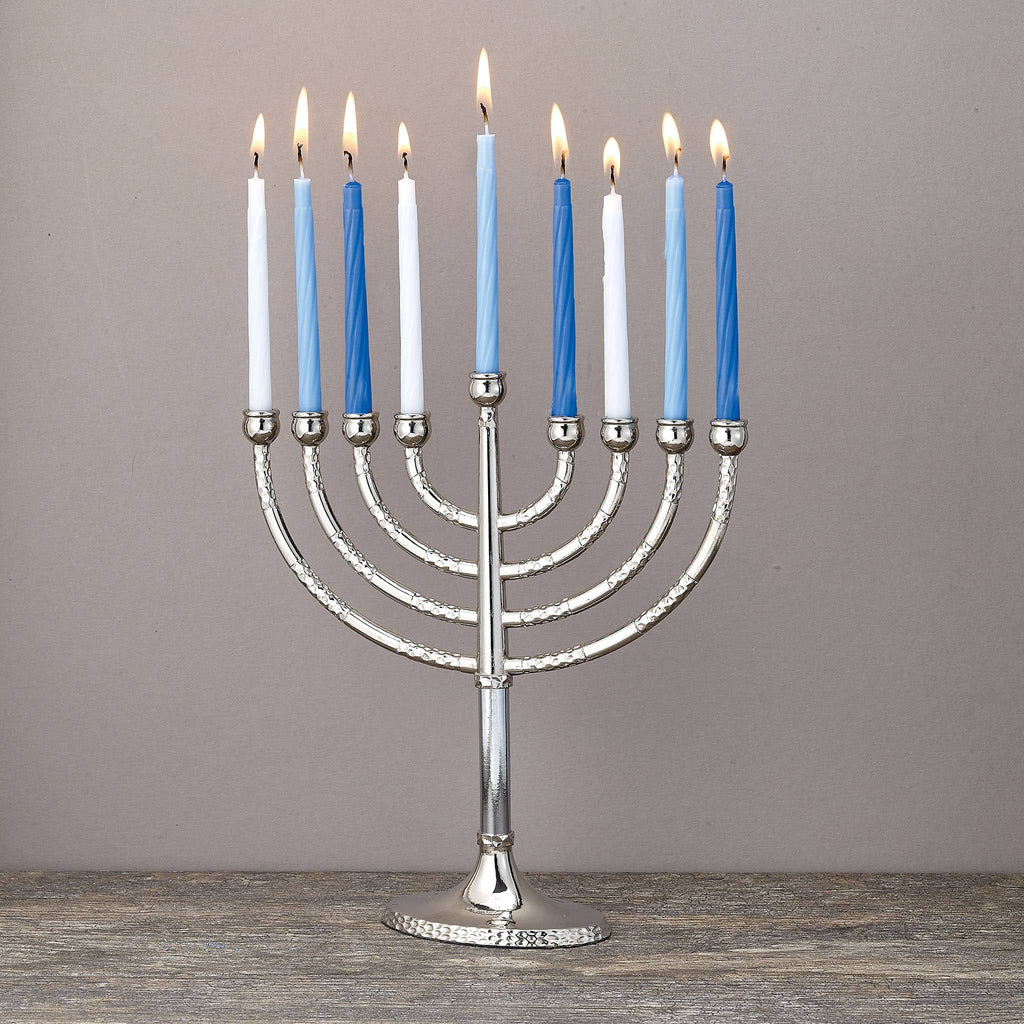 Silver Menorah with blue lit candles on a wooden surface and gray background.