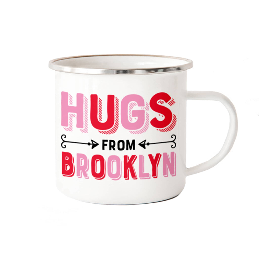 White metal mug with 'Hugs from Brooklyn' text in pink and red on a white background.