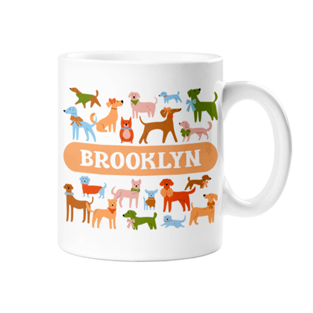 Colorful dogs in assorted shapes and sizes on a white ceramic mug with "Brooklyn" in an orange bar, handle on right, on white background.
