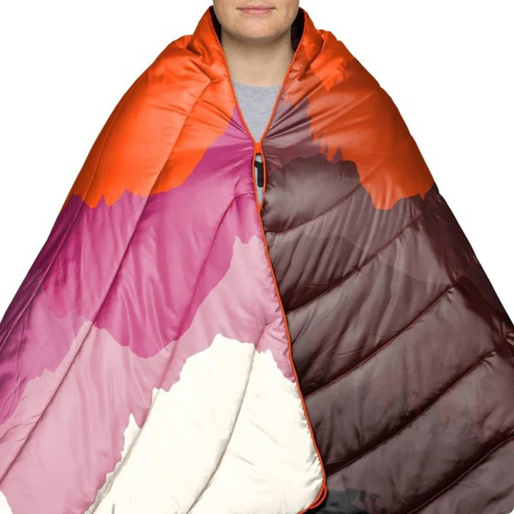 Person wrapped in a colorful puffy blanket with orange, pink, and brown gradient.