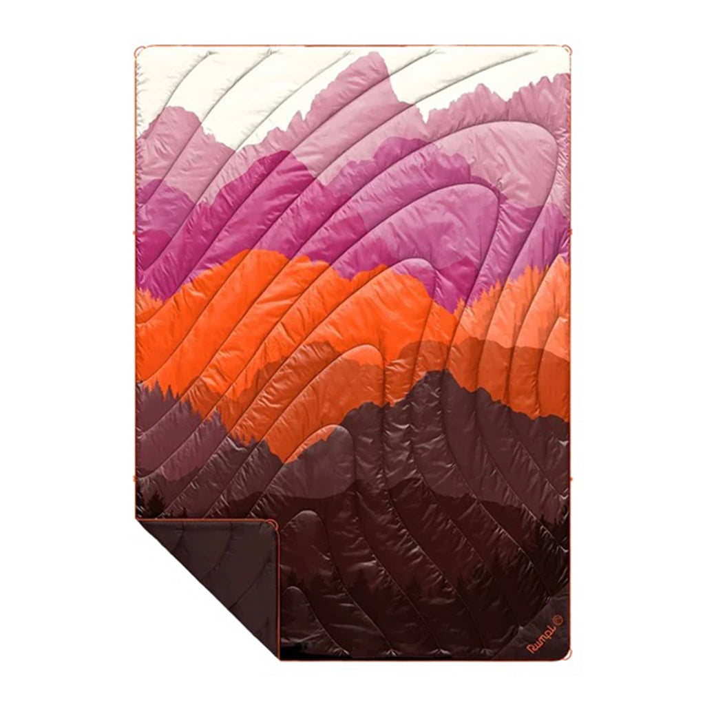 Rumpl Teton Dusk original puffy blanket with an abstract mountain design in brown, orange and purple, flat with corner folded back, on a white background.