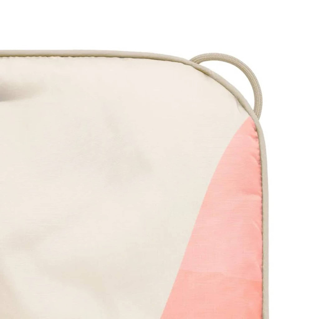 Close-up of the corner of a puffy blanket with a pink and beige color scheme on a white background.
