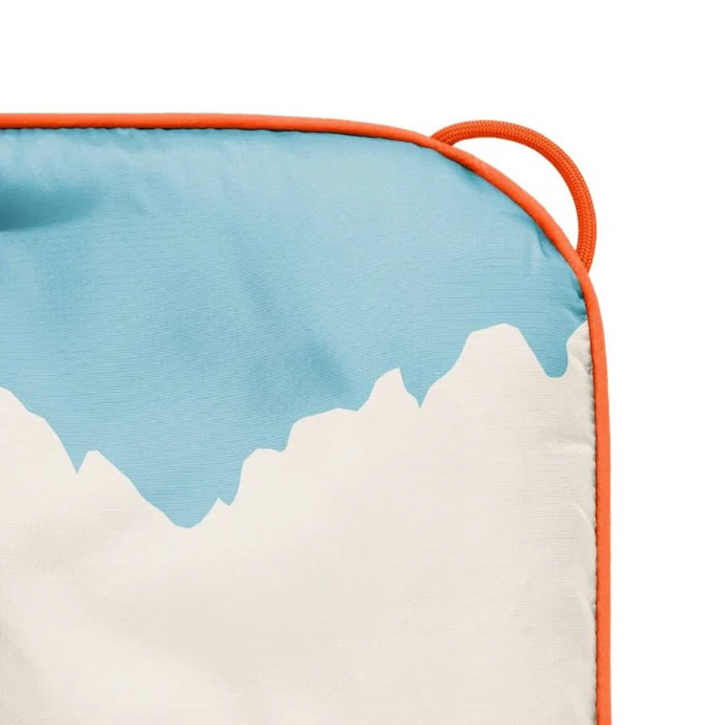 Close-up of a puffy blanket corner with blue, orange, and white design on a white background.