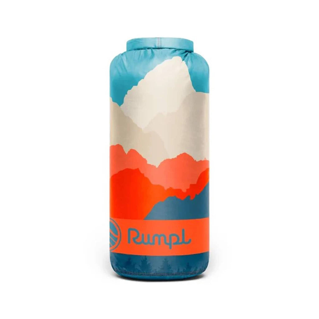 Rumpl Teton Glow original puffy blanket with an abstract mountain design in blue, orange and beige, in matching stuff sack carrier, on a white background.