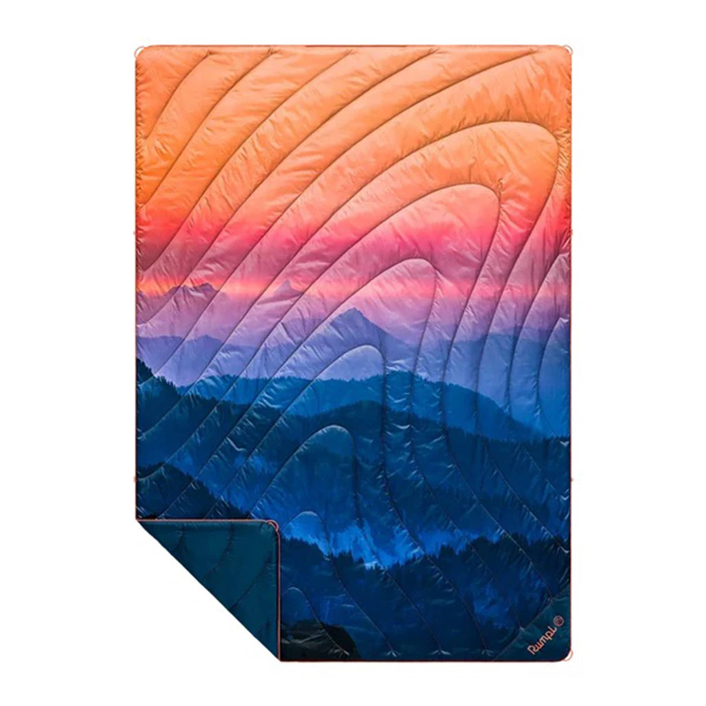 Rumpl Alpenglow original puffy blanket with mountain sunrise image in blue and orange, flat with corner folded back.