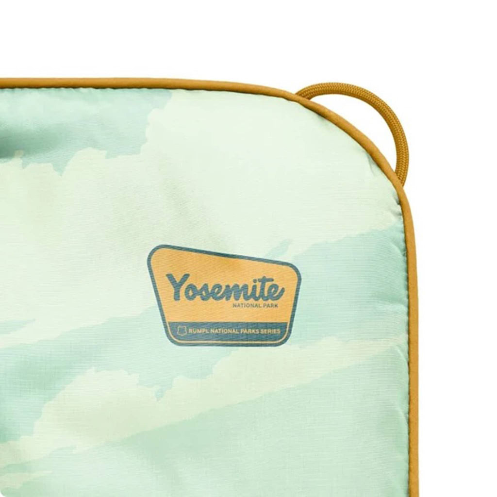 Corner detail of puffy blanket with Yosemite National Park logo on a light green background, on a white background.