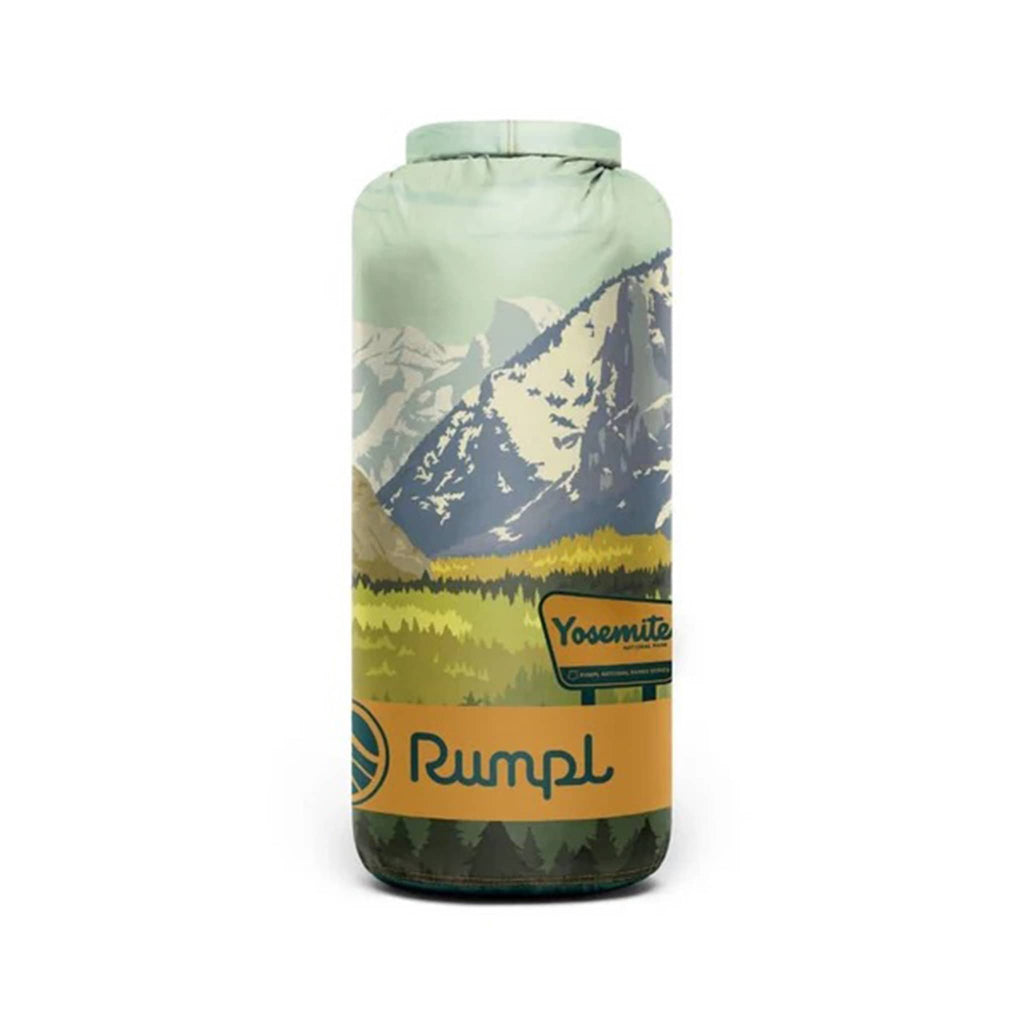 Rumpl Yosemite National Park original puffy blanket with a mountain landscape design, rolled up in matching stuff sack carrier, on a white background.