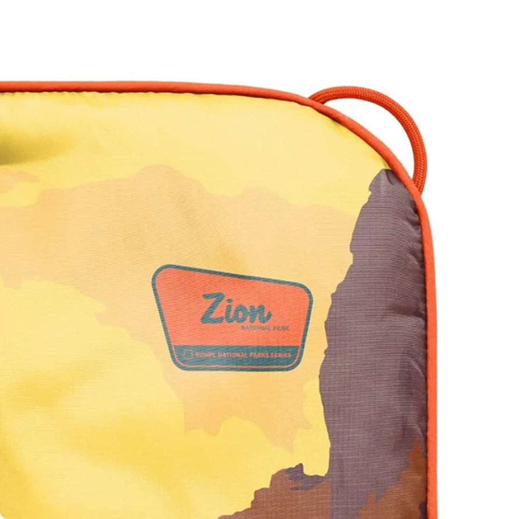 Corner detail of yellow puffy blanket with Zion National Park logo on a white background.