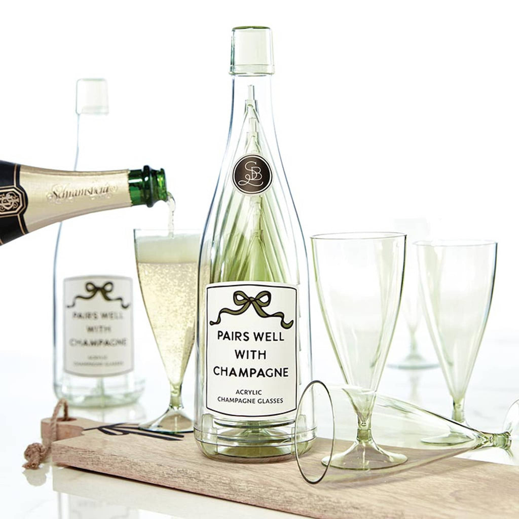 Acrylic bottle labeled 'Pairs Well with Champagne' with 5 green-tinted acrylic champagne flutes on a white background, champagne is being poured into one of the glasses.