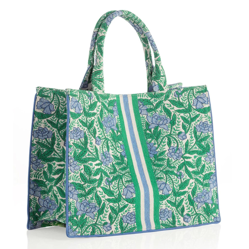 Shiraleah Melanie cotton canvas tote bag with blue and green floral print on white backdrop and green, blue and white racer stripes down the middle of the bag, front angle view.