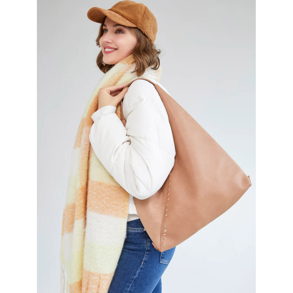 Shiraleah ryker hobo in tan pebbled and suede faux leather with gold studs on models shoulder.