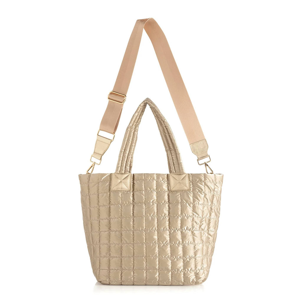 Matte gold quilted tote with crossbody strap on a white background.