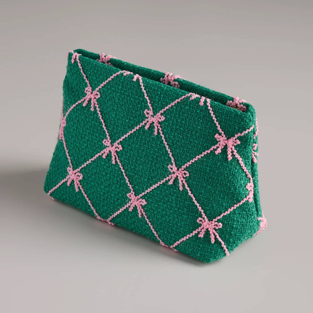 Green clutch with pink bow pattern, front angle, on a gray background.