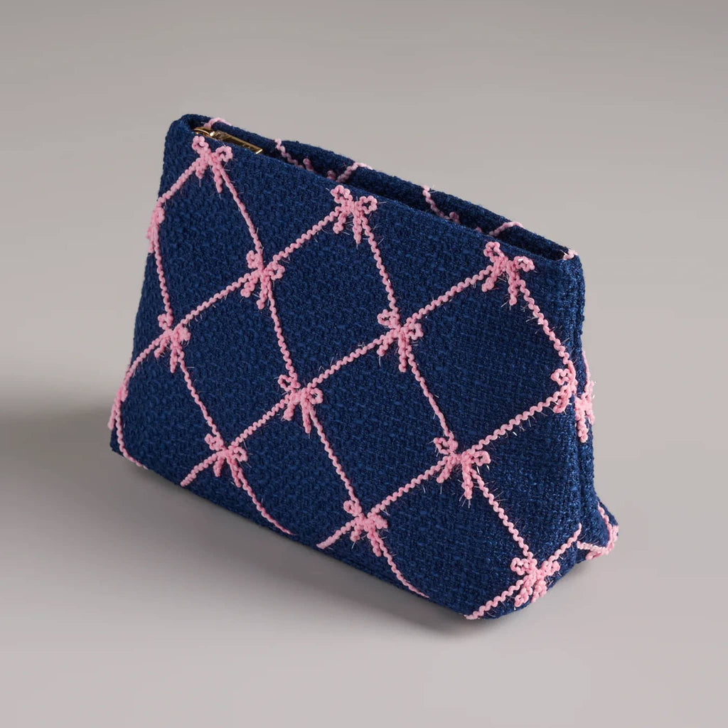 Navy pouch with pink bow pattern, front angle view, on a gray background.