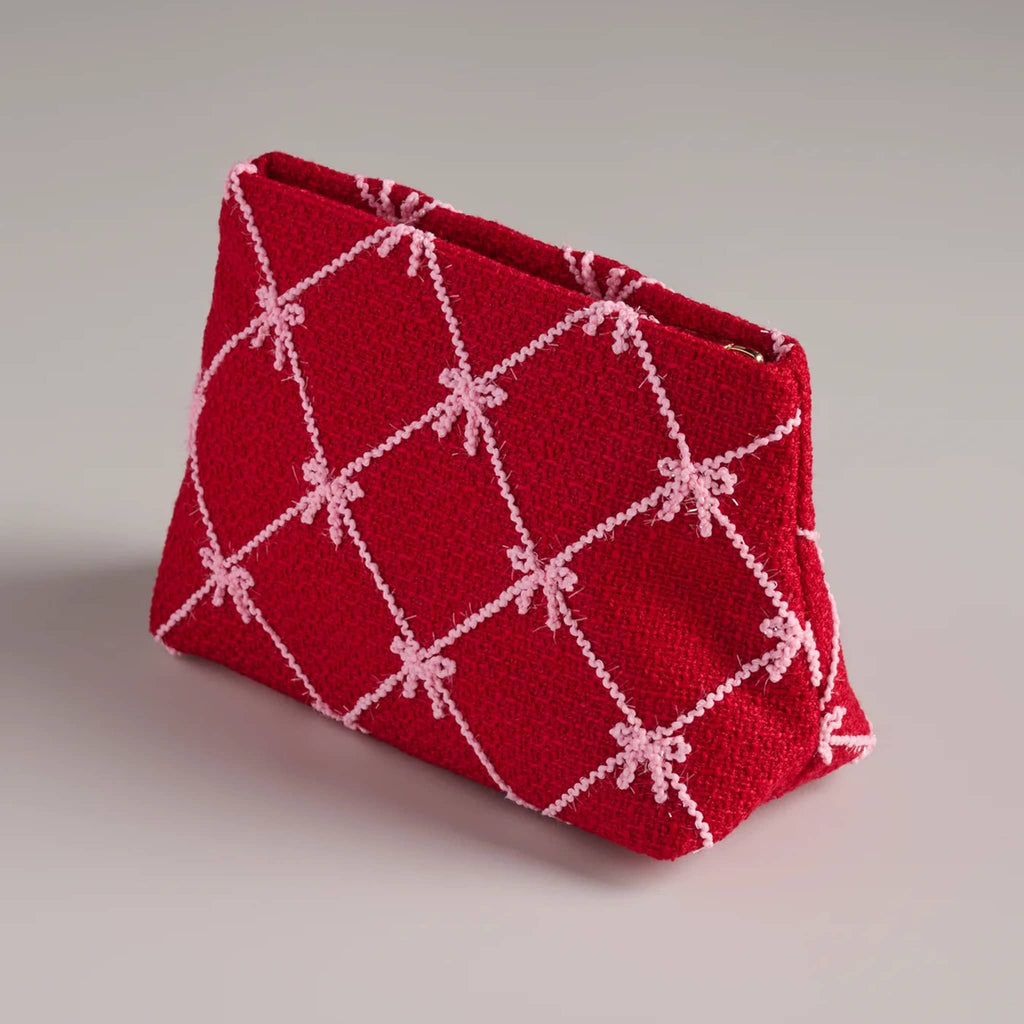 Red clutch with pink bow pattern, front angle, on a gray background.