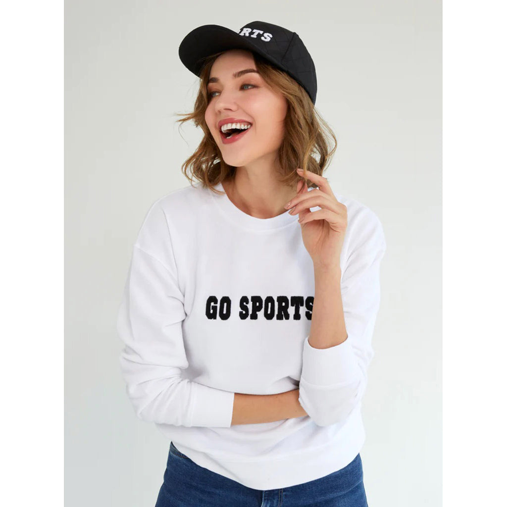 Shiraleah white sweatshirt with "go sports!" in back lettering on the front, on model with black "sports" ball capl