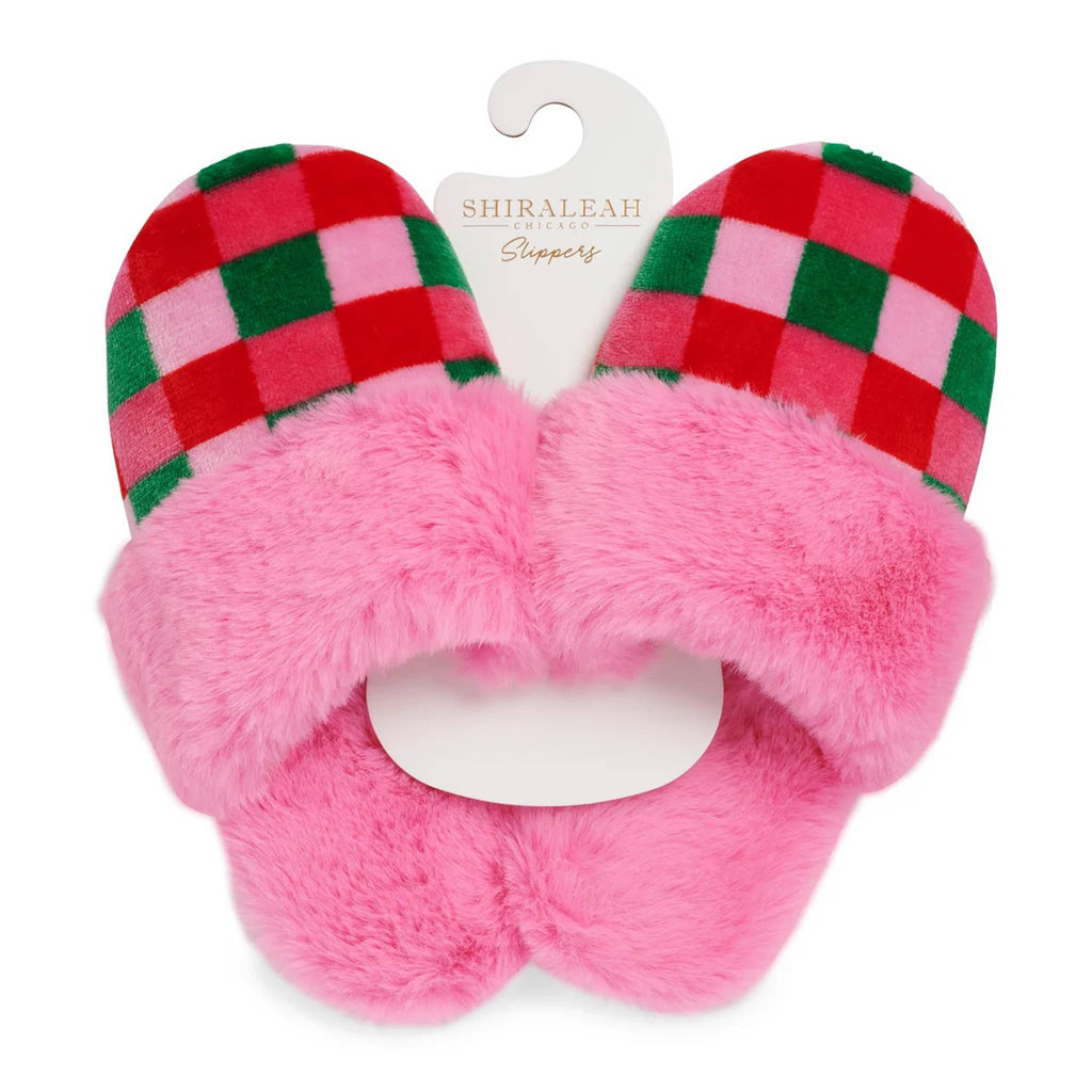 Pair of pink fuzzy slippers with pink, red and green checkered front, with hanger packaging, on a white background.