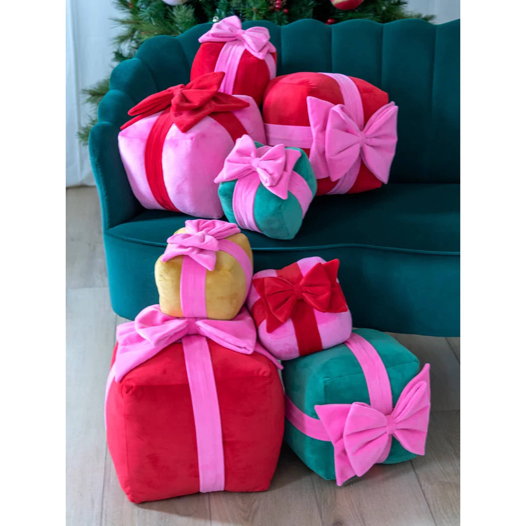 Shiraleah Gift Box Plush Pillows in 3 sizes and 4 colors on a green velvet sofa.