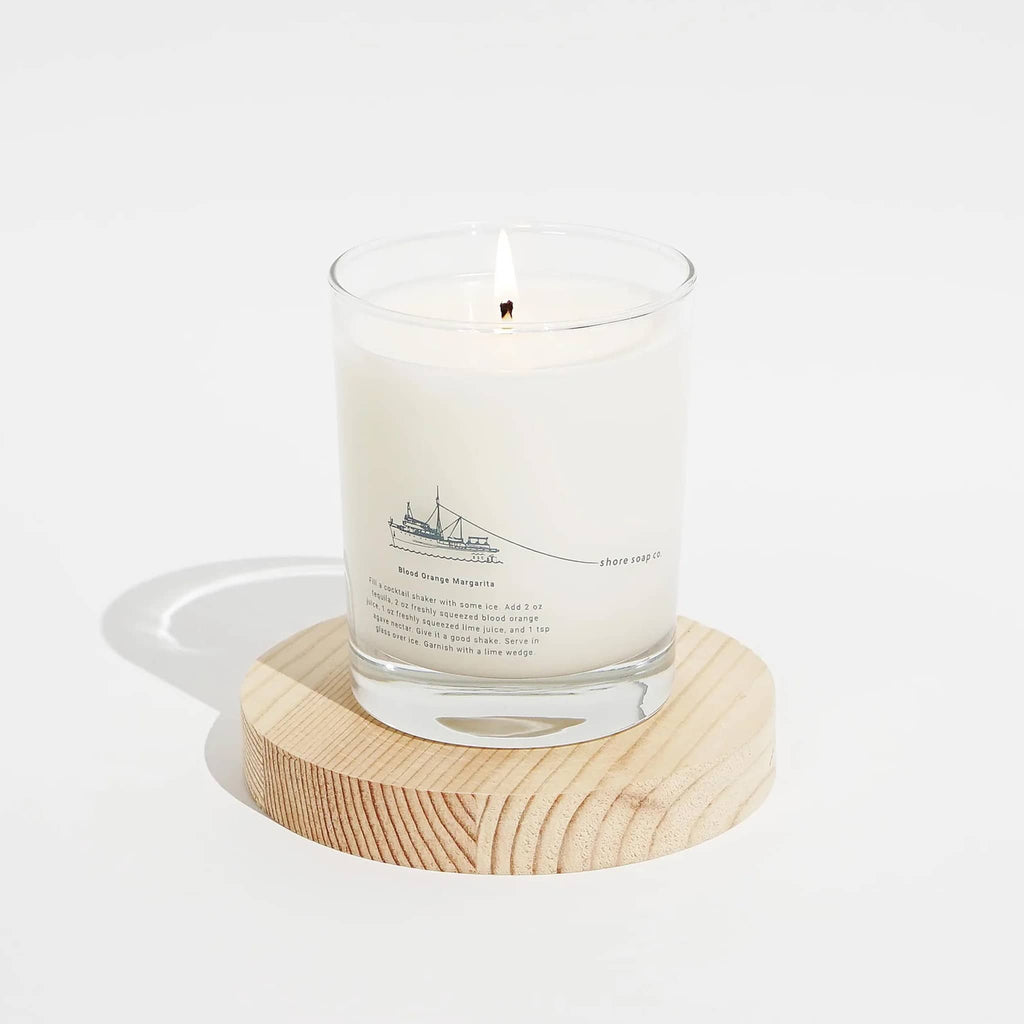 Shore Soap Co. Atlantic scented soy wax 9 ounce candle in glass vessel, wick lit with cocktail recipe printed on glass.