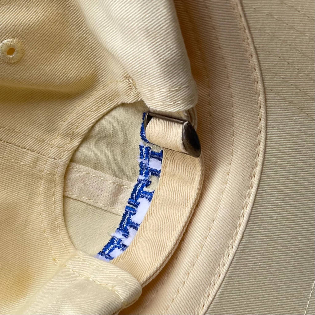 Silver Spider soft yellow unisex baseball cap with "butter" in blue embroidered letters on the front, back view showing adjustable slide tab.