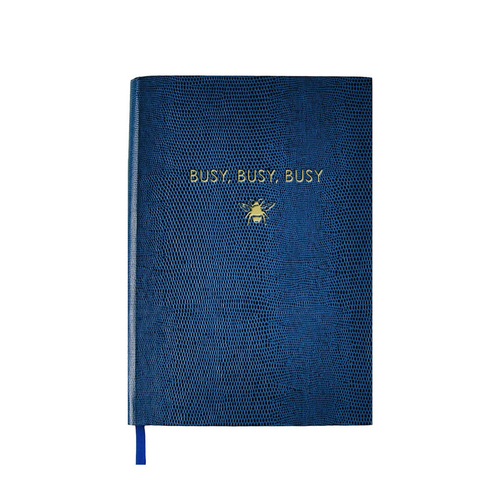 Front cover of a blue faux lizard notebook with "busy, busy, busy" and a bee graphic in gold foil, on a white background.