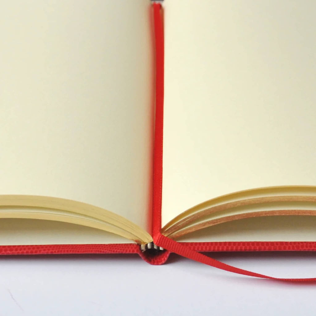 Open notebook with blank cream pages and a red ribbon page marker, on a white background.