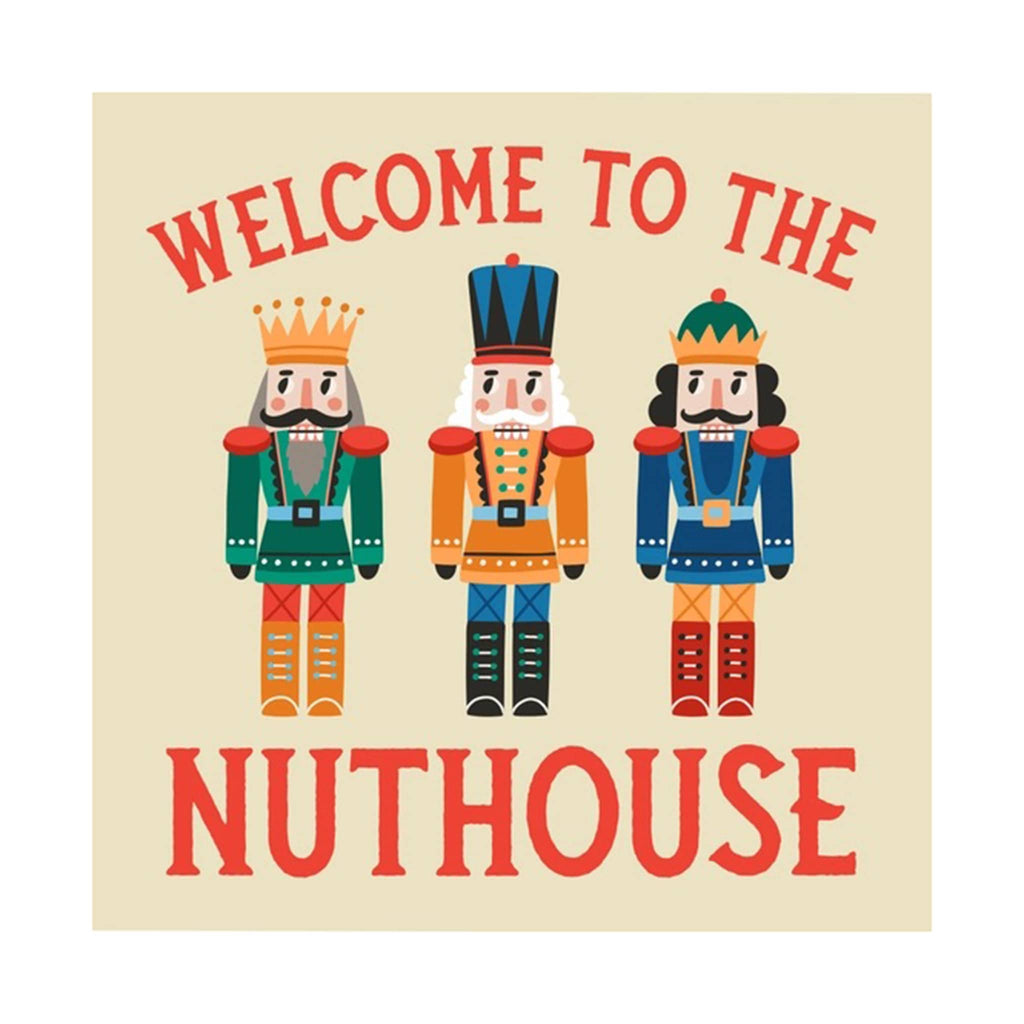 Beige napkin with colorful nutcracker figures and "welcome to the nuthouse" in red lettering.