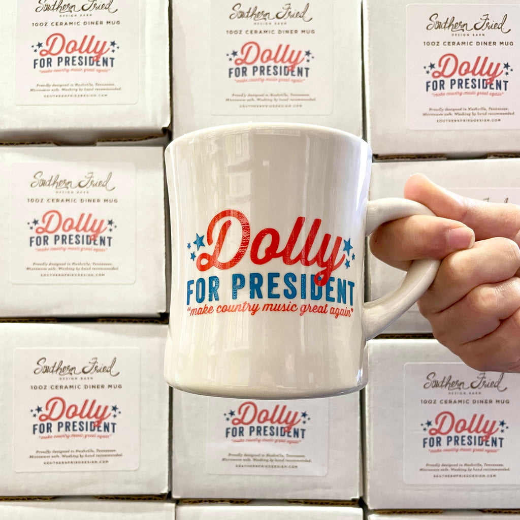 Southern Fried Design Dolly for President campaign ceramic diner mug in front of stack of boxes it comes in.