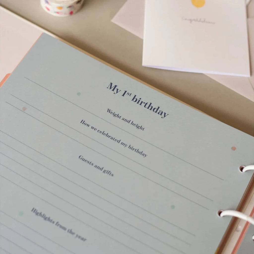 Memory book with 'My 1st birthday' section on a table.