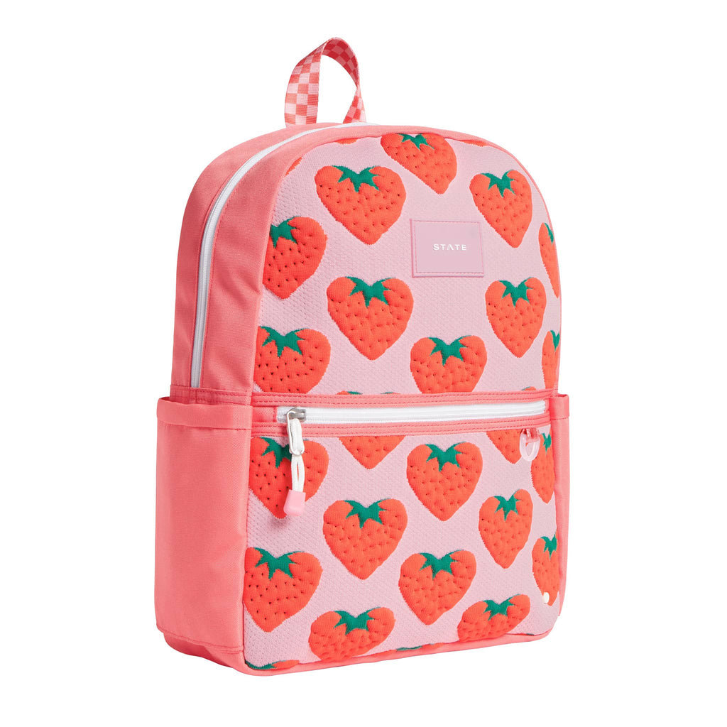 State Bags Kane Kids Backpack with red strawberries on a pink backdrop, front angle view.