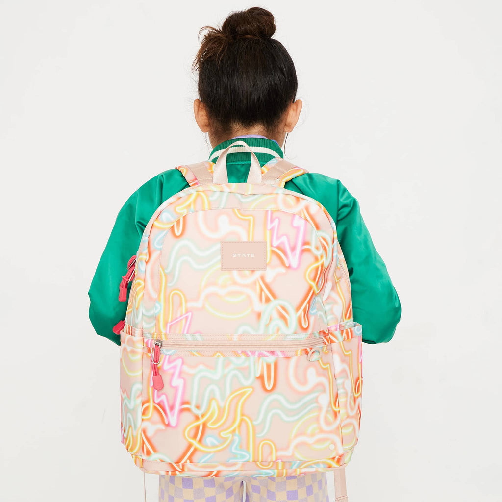 State Bags Kane Kids Double Pocket Backpack in Oversized Neon, shown on a child's back for size.