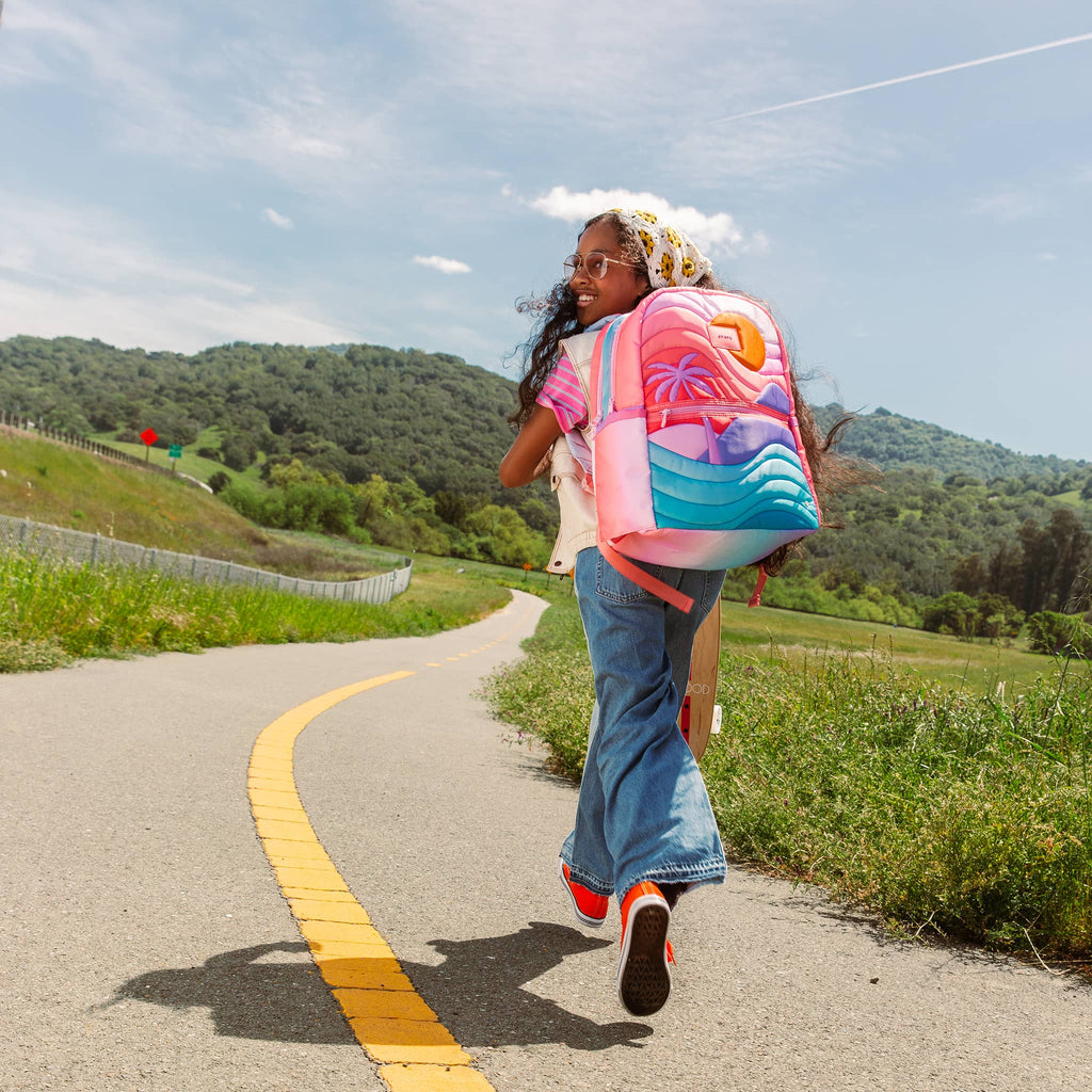 State Bags Kane Kids Double Pocket Backpack in Sunset, on child's back walking down a country road for scale.