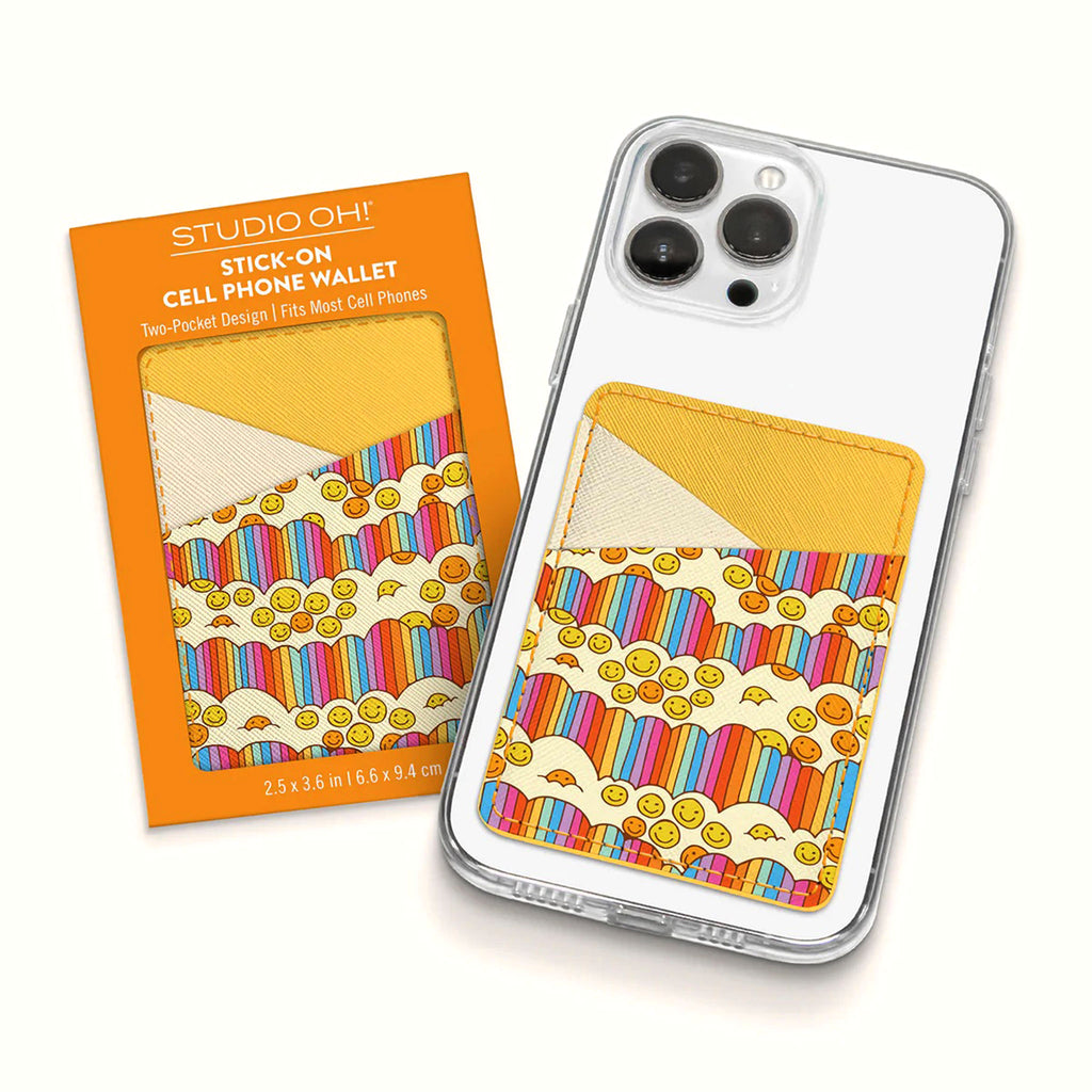 Studio Oh! Good Times Stick-On Cell Phone Wallet with with pale and golden yellow pocket design, rainbow striped clouds and smiley faces. Shown in packaging and attached to the back of a phone.