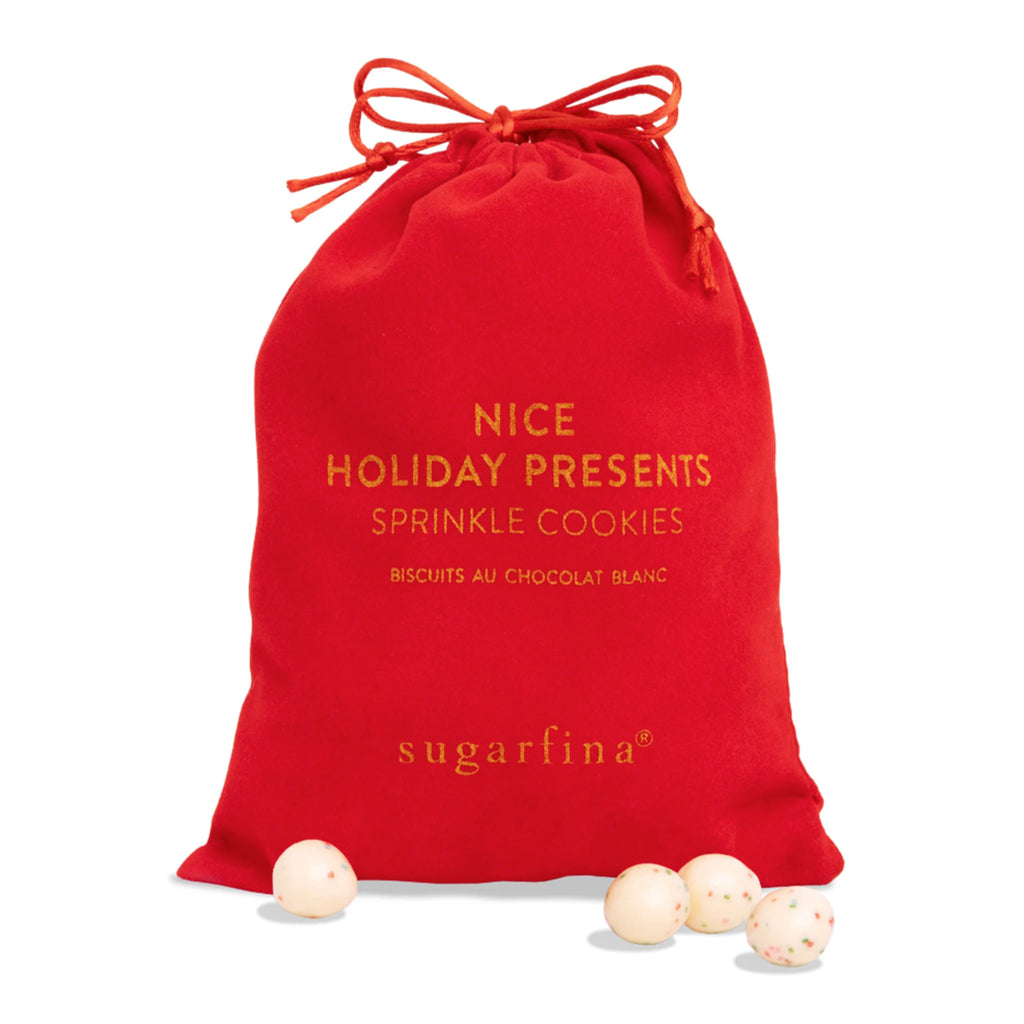 Sugarfina Holiday Presents Sprinkle Cookies candy in inner red drawstring bag with round white chocolate balls with red, blue, pink and green sprinkles in front.