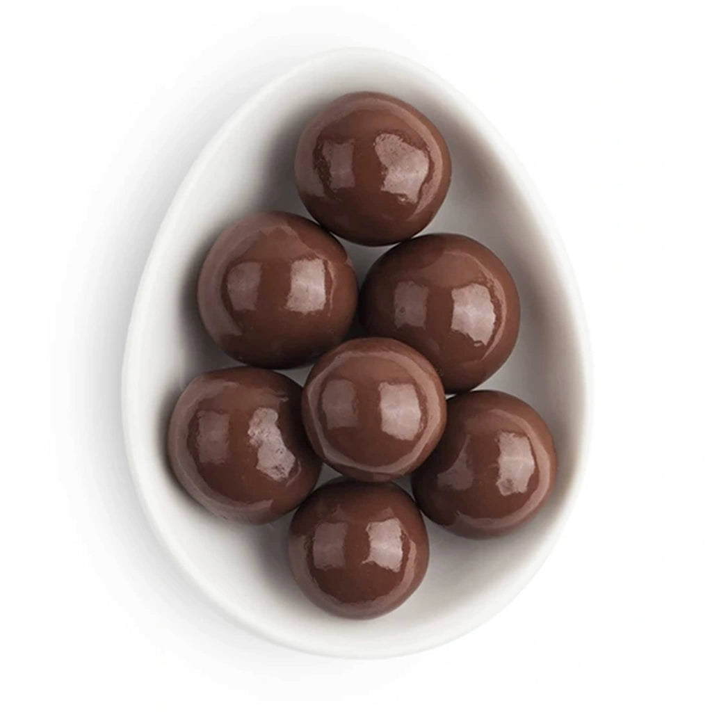 Chocolate balls in a white oval dish, on a white background.