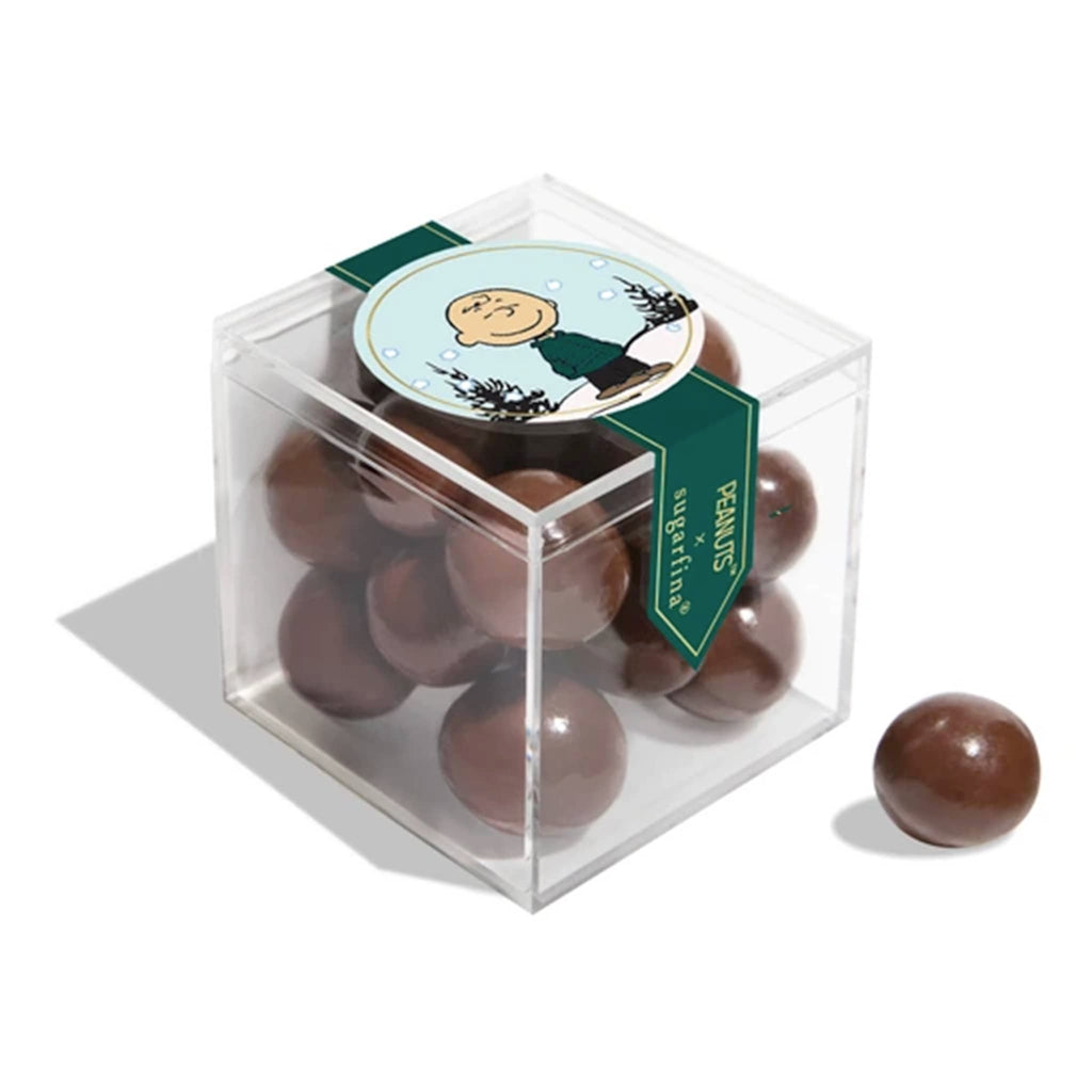 Clear cube box with Charlie Brown on the top, filled with chocolate balls, on a white background.