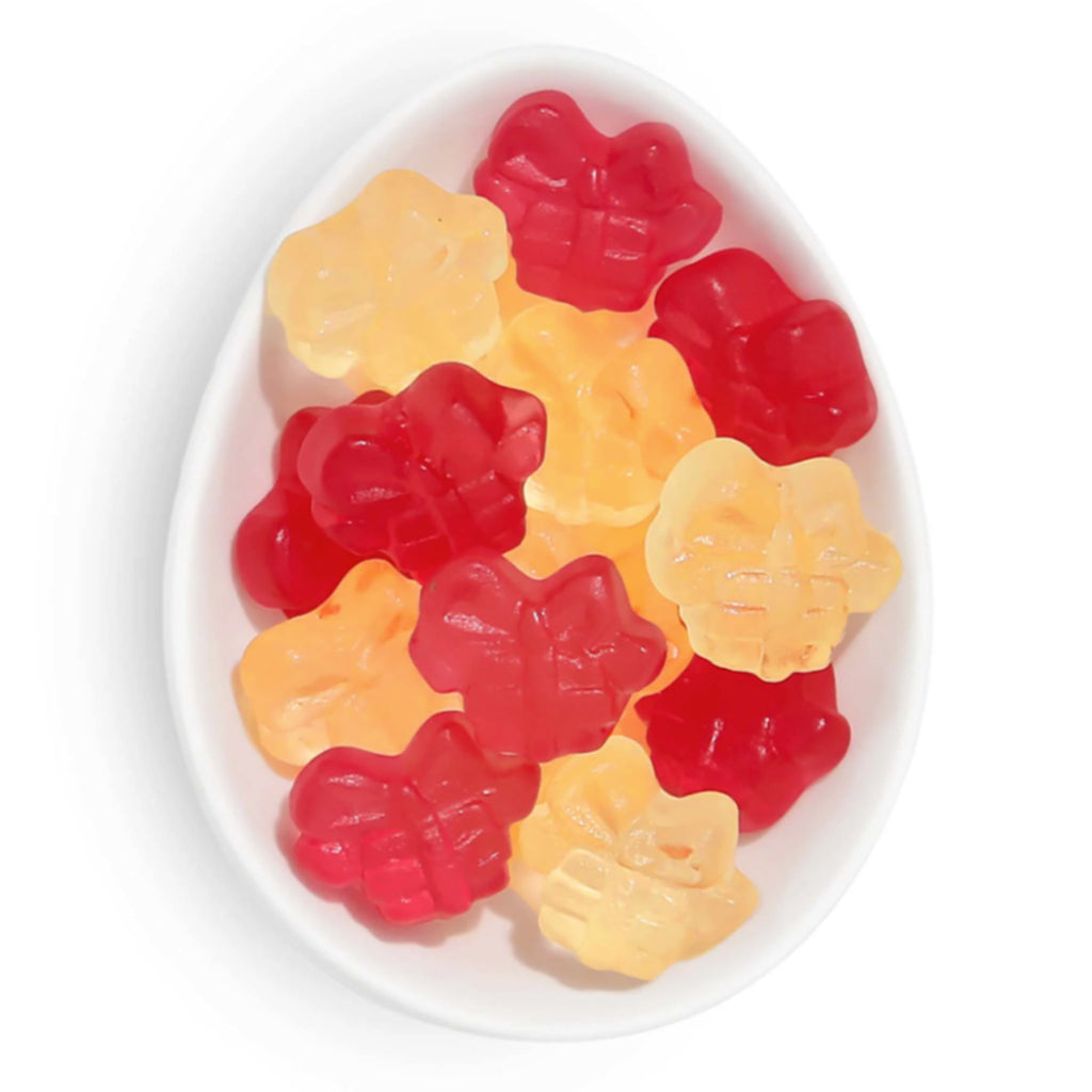 Sugarfina Penguin Presents red and yellow present shaped holiday gummy candy in a white oval dish.
