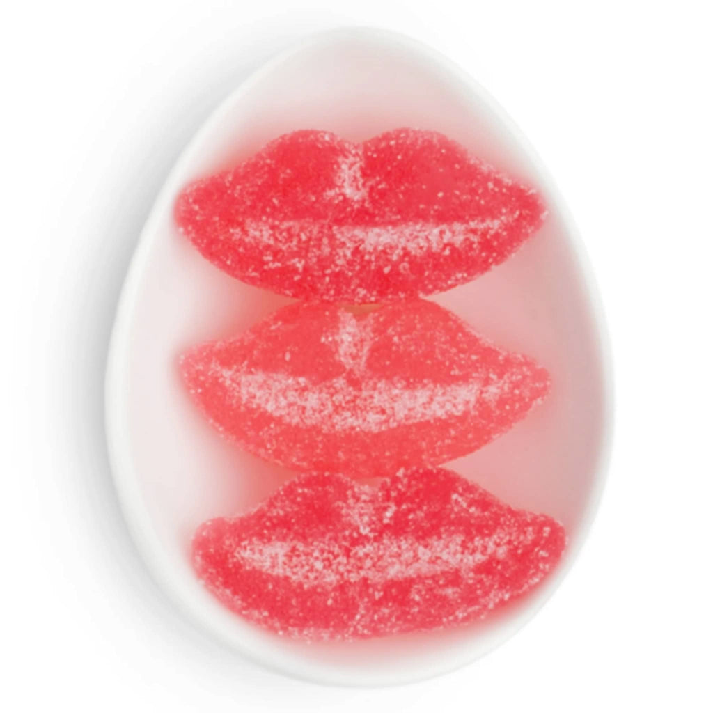 Red lip-shaped candy with sugar sprinkles in a white oval dish, on a white background.