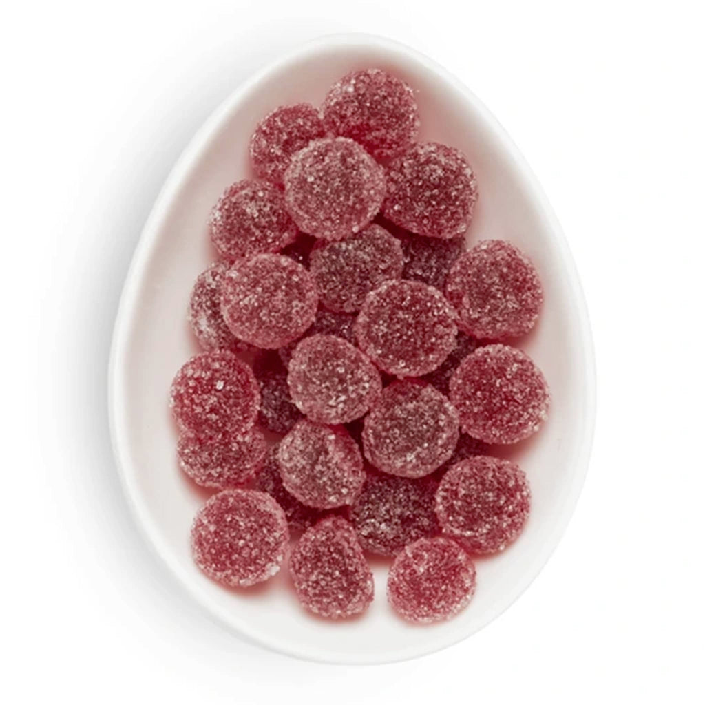 White oval plate with red gummy candies on a white background.