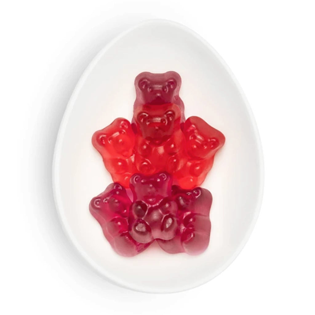 Red gummy bear candies on a white oval dish, on a white background.