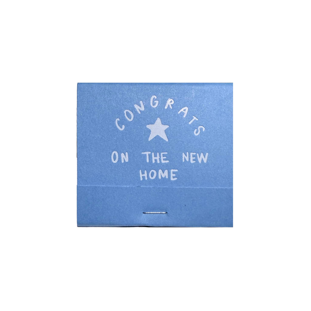 Blue matchbook with white text 'Congrats on the new home' and a star on a white background.