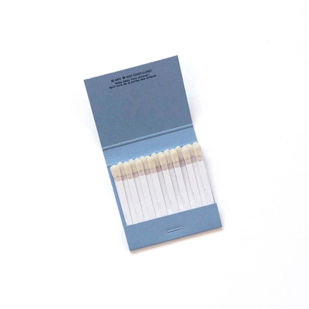 Open blue matchbook with white matches on a white background.
