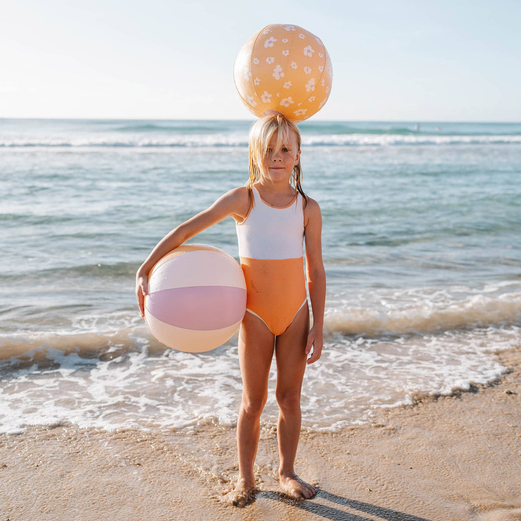 Sunnylife Princess Swan Inflatable Beach Balls, set of 2, one is pale orange with white flowers, the other is pink, white and orange striped, both with a girl on the beach.